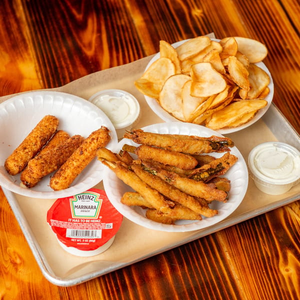 A tray of fried mozzarella sticks, fried okra, and potato chips with dipping sauces.